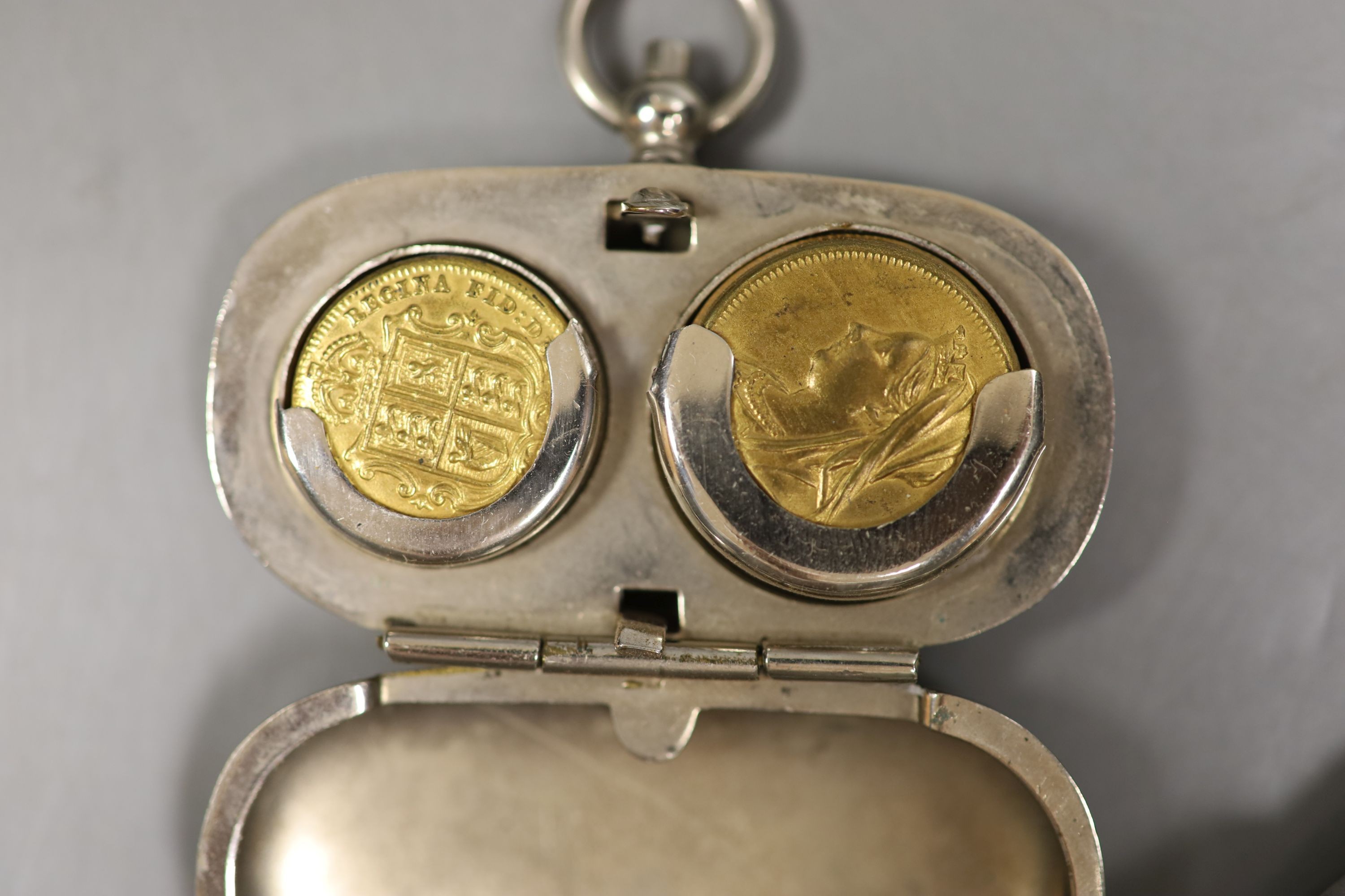 A silver plated sovereign case with faux sovereigns and a childs rattle.